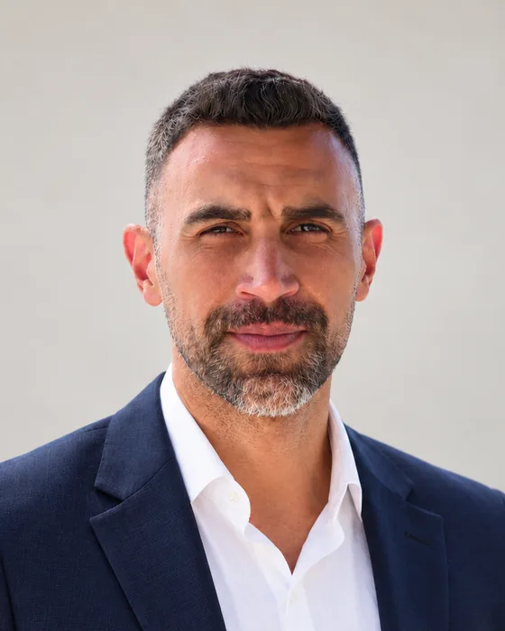Deniz Kaya, consultant solicitor, in a navy jacket and white open-collar shirt